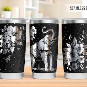 May include: Stainless steel tumbler with a black background and a silver elephant design. The tumbler also features silver flowers, butterflies, and the text "SEAMLESS DESIGN".