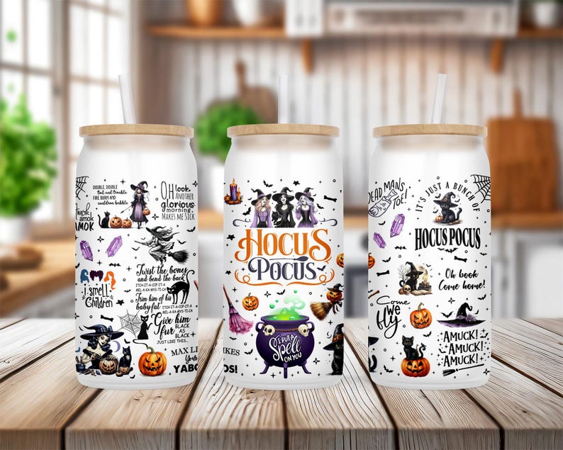 K&ouml;nnte beinhalten: Drei wei&szlig;e isolierte Becher mit schwarzen Deckeln und Bambusstrohhalmen. Jeder Becher zeigt ein anderes Halloween-Design mit schwarzen Katzen, Hexen, K&uuml;rbissen und dem Text "Hocus Pocus".