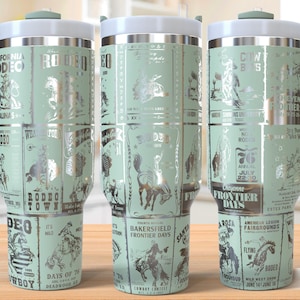 May include: A green stainless steel travel mug with a handle. The mug has a silver design with a pattern of rodeo scenes and text that says "California Frontier Days" and "Rodeo Town".