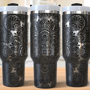 May include: Three black stainless steel tumblers with a silver mandala design and the phrase "This is Bullshit" repeated around the design. The tumblers have a black handle and lid.