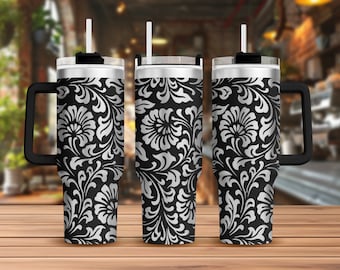 May include: A black and silver stainless steel tumbler with a floral pattern and a black handle. The tumbler has a lid and a straw.