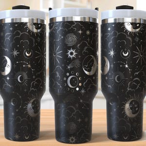 May include: A black stainless steel travel mug with a silver design of moons, stars, and clouds. The mug has a handle and a lid. "Seamless Design" is printed on the bottom right corner of the image.