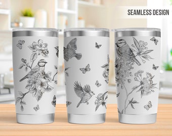 May include: Three white stainless steel tumblers with a black and white floral and bird design. The design features a repeating pattern of birds, flowers, and butterflies. The tumblers are seamless and have a white background.
