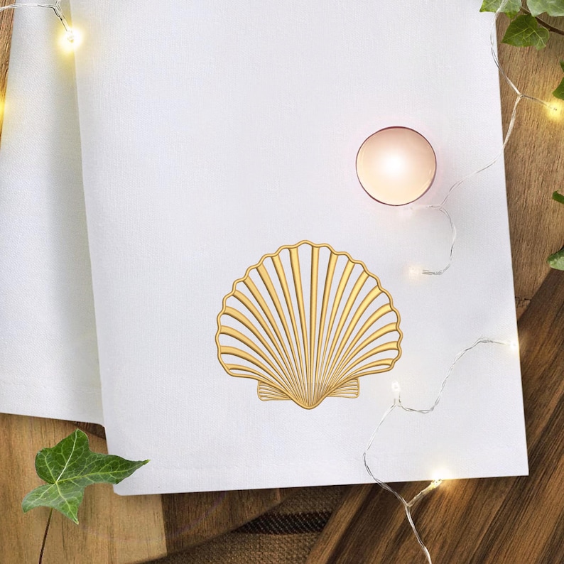 May include: White linen napkin with a gold seashell design. A small, round, pink candle sits near the top right corner. The napkin is on a wooden surface, with a few green leaves and string lights.