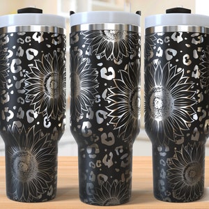 May include: Black stainless steel tumbler with a silver sunflower and leopard print design. The tumbler has a lid and a handle.