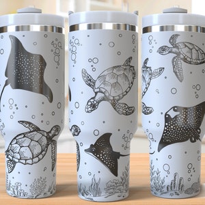 Op de afbeelding: Een witte roestvrijstalen reistumbler met een zwart-wit ontwerp van zeeschildpadden en mantaroggen. De tumbler heeft een handvat en een deksel. Het ontwerp is naadloos en loopt rond de hele tumbler.