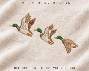 May include: An embroidery design featuring three mallard ducks in flight, arranged diagonally on a textured off-white fabric. The text EMBROIDERY DESIGN appears at the top, with file formats DST, EXP, HUS, JEF, PES, VP3, CND, XXX below.