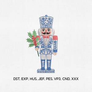 May include: An embroidery design of a nutcracker wearing a blue and white uniform with floral patterns, a red bowtie, and a tall hat. The figure holds a green holly branch with red berries. Text below reads: DST, EXP, HUS, JEF, PES, VP3, CND, XXX.