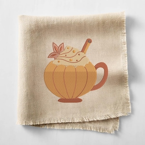May include: A beige linen napkin with a pumpkin spice latte design. The embroidered latte features a pumpkin-shaped cup, whipped cream, a cinnamon stick, and a decorative leaf. The napkin has a fringed edge.