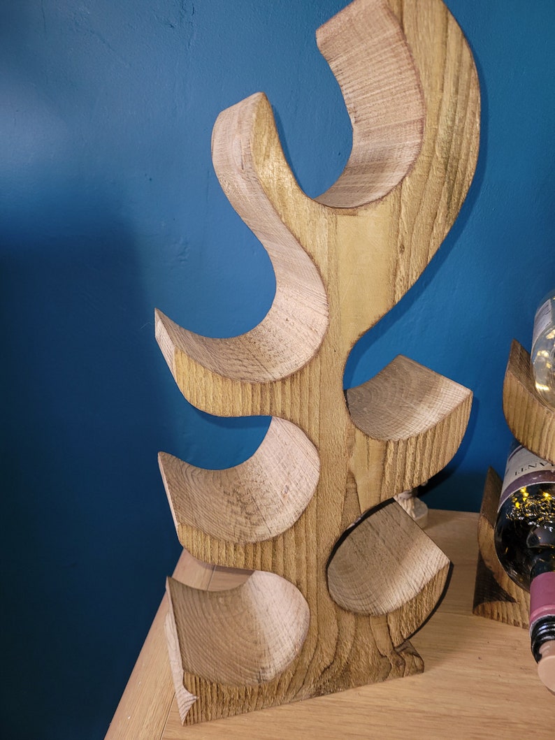 May include: Wooden wine rack shaped like a tree with five bottle holders. The rack is made of light brown wood and has a natural finish.