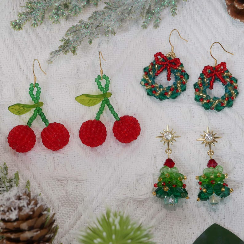 May include: A collection of beaded earrings in festive designs. Includes cherry, wreath, and Christmas tree shapes. The earrings feature red, green, and gold beads with gold-colored hooks. Perfect for holiday or seasonal wear.
