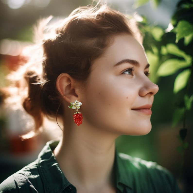 May include: A woman with red hair wearing a green shirt and gold earrings with a white flower and red berry design.