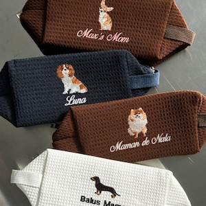 May include: Four rectangular zippered pouches with a waffle-textured fabric. The top brown pouch features an embroidered dog and the text Max's Mom. The navy pouch shows a dog and the text Luna. The middle brown pouch has a dog and Maman de Nala. The white pouch displays a dachshund and Balus Mama.