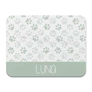 May include: A light green pet placemat with a paw print pattern and the name "LUNA" written in white.