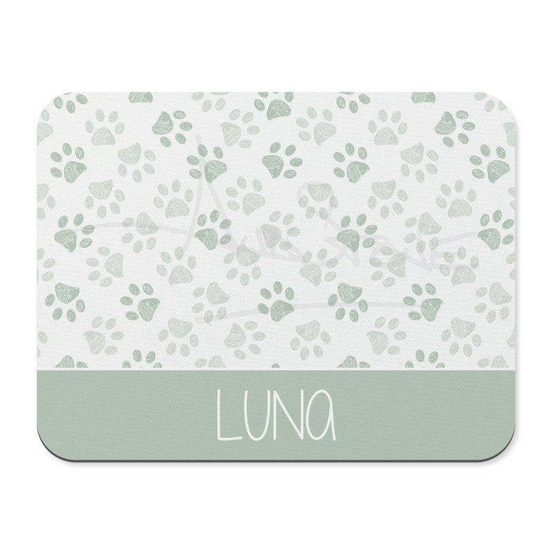 May include: A light green pet placemat with a paw print pattern and the name "LUNA" written in white.