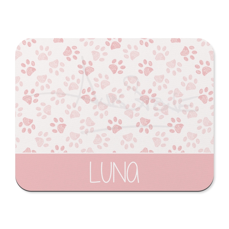 May include: Pink mouse pad with a white background and a pattern of pink paw prints. The bottom of the mouse pad has a solid pink band with the name "LUNA" written in white.