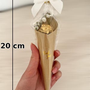 May include: A cone-shaped gift package, approximately 8 inches tall, made of brown paper, containing a gold-wrapped chocolate and small white flowers. The package is tied with a white bow and cellophane. The text "Thank You!" is printed on the cone.