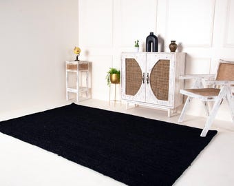 May include: A black area rug with a white, two-door cabinet with woven cane panels, a white chair with woven cane seat and back, and a small white side table with a globe on top.