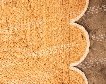 May include: A natural fiber rug with a scalloped edge. The rug is made of woven jute and has a light brown color. The rug is on a gray concrete floor.