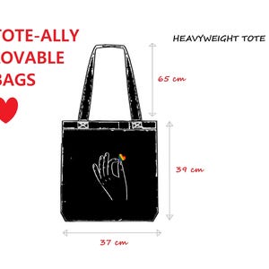 A diagram of a black heavyweight tote shows its dimensions. On the bag is a simple image of a hand holding a rainbow heart.