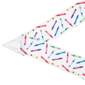 May include: White ribbon with a repeating pattern of colorful crayons. The crayons are arranged in a random pattern and are all different colors.