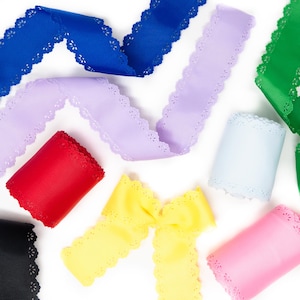 May include: Assortment of colorful ribbons in various shades, including blue, purple, red, yellow, pink, green, black, and white. Each ribbon features a scalloped edge. Ribbons are arranged on a white background.