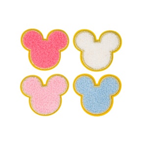 May include: Four fuzzy felt Mickey Mouse head patches in pink, white, light pink, and light blue. Each patch has a yellow outline.