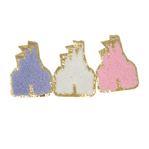 May include: Three felt castle patches with gold glitter trim. The castles are in purple, white, and pink.
