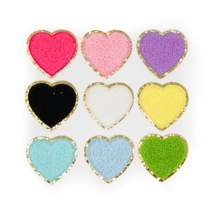 May include: Nine felt heart-shaped patches with gold glitter trim. The patches are in various colors: pink, purple, yellow, black, white, light blue, and green.