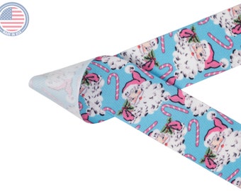 May include: Blue and white ribbon with a repeating pattern of Santa Claus and candy canes. The ribbon is folded in half, showing the white backing.