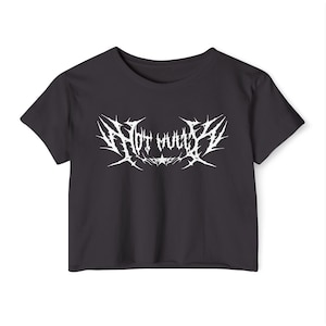 May include: Black crop top with the white text "Hot Mud" in a spiky, gothic font. The shirt has short sleeves and a crew neck. The text is centered on the front of the shirt.