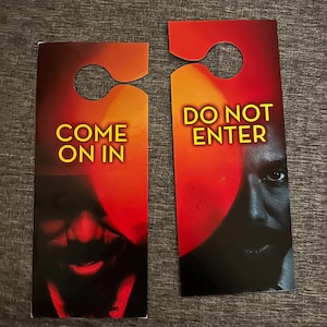 Puede incluir: Dos colgadores de puerta con un fondo degradado rojo y naranja. Uno dice "COME ON IN" en texto amarillo, y el otro dice "DO NOT ENTER". Ambos presentan un rostro sombreado.