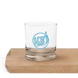 May include: A clear glass tumbler with a blue logo that says "SEB's" with a musical note above the "B". The logo is inside a circle with a wavy line around it.