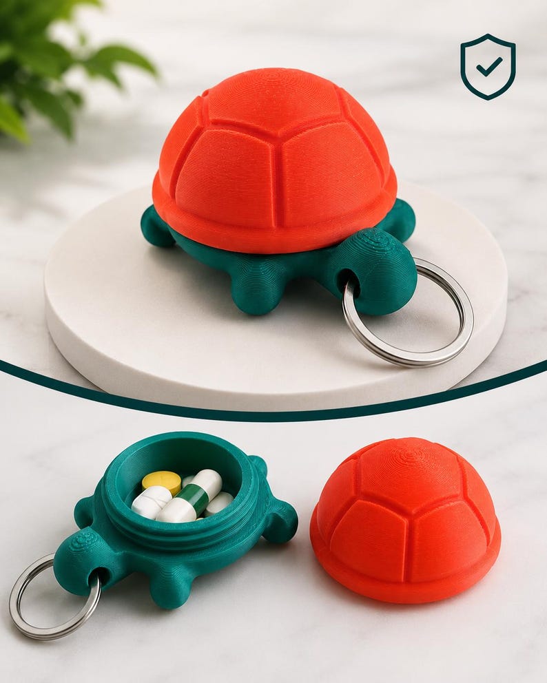 以下が含まれることがあります： 鮮やかなオレンジとティール色の3Dプリントされたカメ型ピルホルダー。カメは取り外し可能な甲羅とキーリングが付いています。開いたホルダーにはいくつかのピルが入っています。薬を持ち運ぶための楽しくて機能的なデザインです。