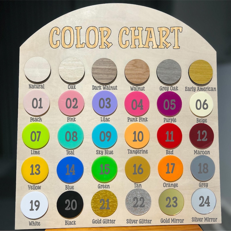 May include: A wooden color chart with the words "COLOR CHART" at the top. It features 24 color samples in various shades, including natural wood, pink, blue, and metallic options. Each color is labeled with a name and a number.