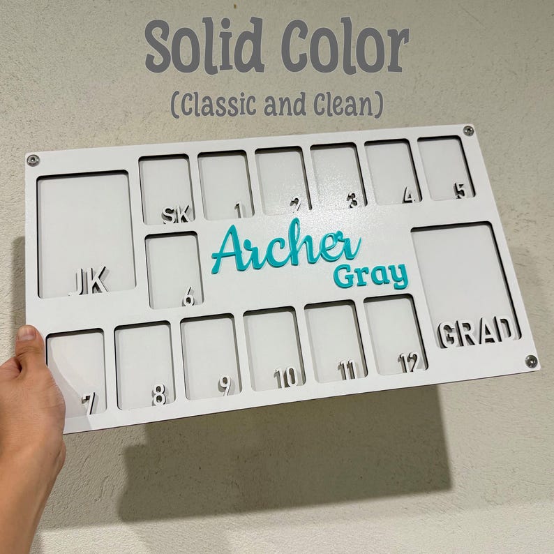 May include: A white wooden board with cut-out rectangular slots and the words "Solid Color" and "(Classic and Clean)" in gray. The name "Archer Gray" is in teal. Numbers and letters are cut out for personalization.