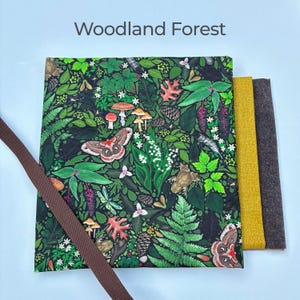 Może przedstawiać: Kwadratowy materiał z leśnym wzorem z grzybami, motylami i liśćmi. Tekst "Woodland Forest" znajduje się na g&oacute;rze. Obok trzy pr&oacute;bki materiału w kolorze ż&oacute;łtym, brązowym i szarym, z brązowym paskiem po lewej stronie.