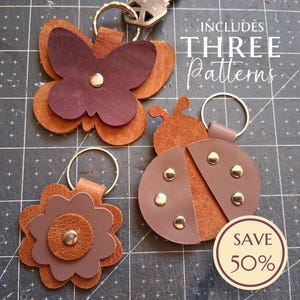 May include: Leather keychains in butterfly, ladybug, and flower shapes. The butterfly is dark brown with a lighter brown outline. The ladybug is brown with gold rivets. The flower is brown with a gold rivet. Includes three patterns.