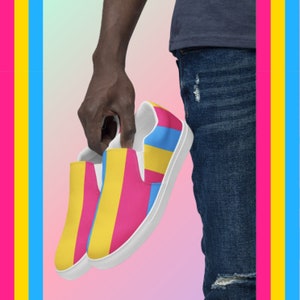 Puede incluir: Un par de zapatos de lona blancos con un patrón de rayas rosa, amarillo y azul. Los zapatos están siendo sostenidos por una persona.