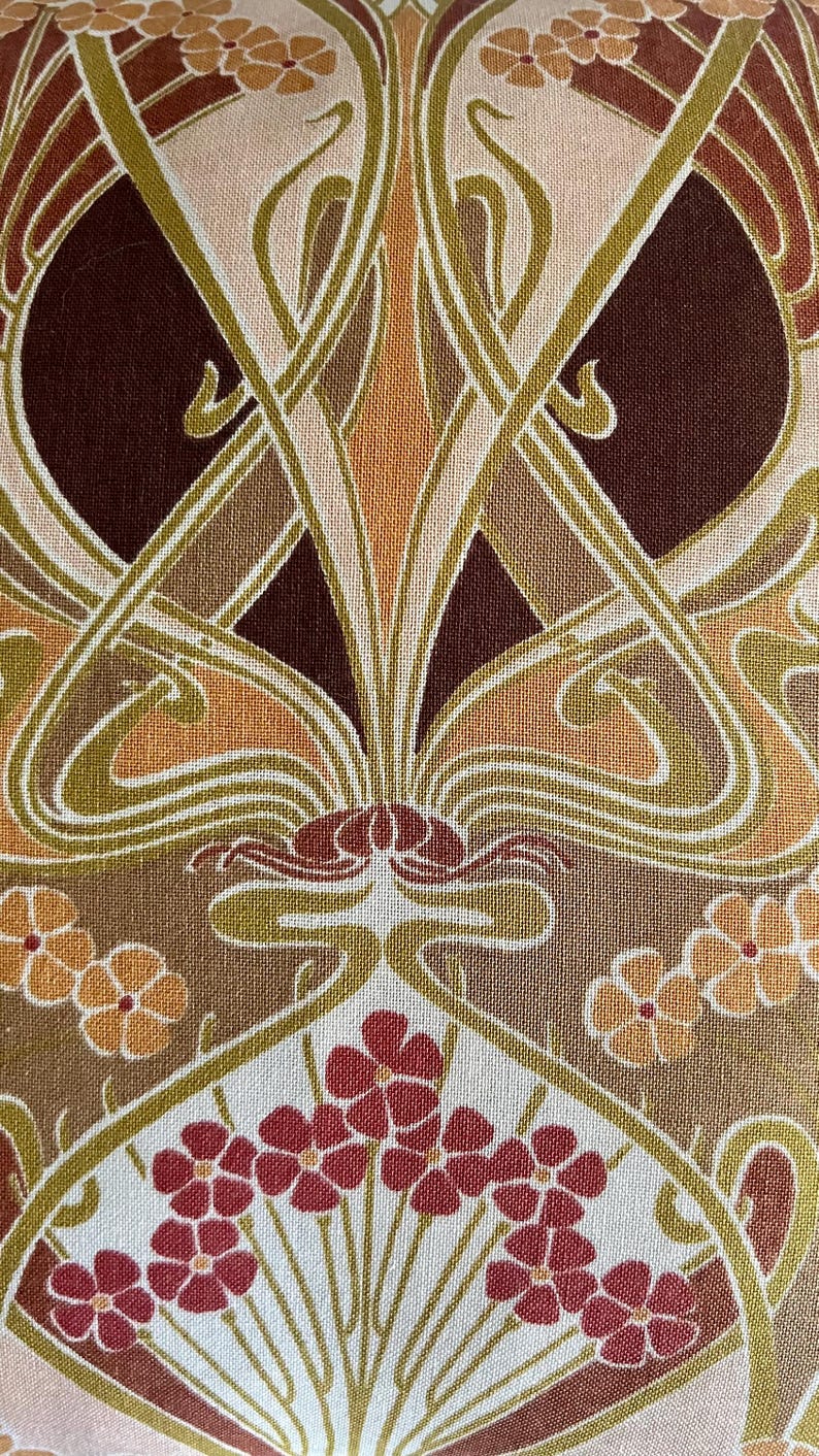 Puede incluir: Primer plano de una tela con un dise&ntilde;o Art Nouveau. El patr&oacute;n presenta formas florales y org&aacute;nicas estilizadas en tonos de marr&oacute;n, beige, naranja y rojo. El dise&ntilde;o es sim&eacute;trico y detallado, con una apariencia texturizada.