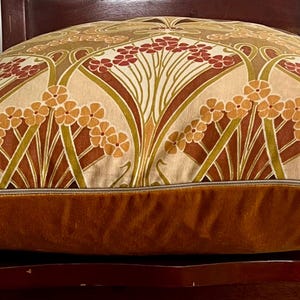 Puede incluir: Coj&iacute;n decorativo con un estampado floral en tonos beige, marr&oacute;n y rojo. Tiene una base de terciopelo marr&oacute;n y un cierre de cremallera. El dise&ntilde;o presenta flores y hojas estilizadas.