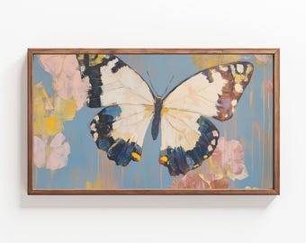 May include: Butterfly painting in a wooden frame. The butterfly has white wings with brown and blue markings. The background is a light blue with pink and yellow floral accents. The frame is a dark brown color.