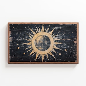 Può includere: Un cartello in legno incorniciato con sfondo nero e un sole dorato con una luna nera al suo interno. Il sole ha un aspetto usurato ed è circondato da piccole stelle dorate.