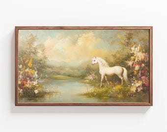 May include: A framed painting of a white unicorn standing in a field of flowers by a lake. The painting has a soft, dreamy feel and is set in a lush, green landscape.