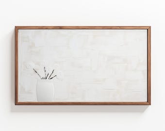 May include: A white vase with black stems and white flowers sits on a white textured background. The vase and flowers are framed in a light brown wood frame.