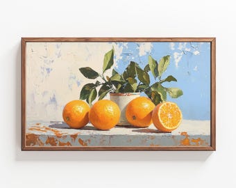 May include: A still life painting of oranges and a small potted plant with green leaves. The oranges are arranged on a table with a blue and white background. The painting is framed in a brown wooden frame.