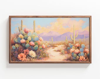 May include: A framed painting depicting a desert landscape with a path leading through a field of blooming cactus flowers. The flowers are pink, white, and yellow, and the cactus plants are green with prickly spines. The background features a hazy purple mountain range and a clear blue sky.