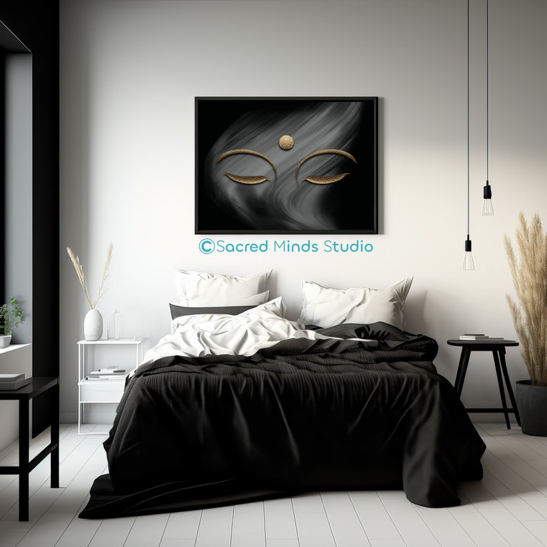 Puede incluir: Una impresi&oacute;n de arte abstracto en blanco y negro con un dise&ntilde;o de ojo de Buda dorado. La impresi&oacute;n est&aacute; enmarcada en negro y colgada en una pared blanca sobre una cama blanca y negra.