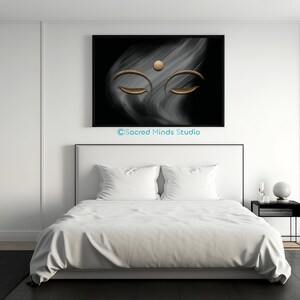 Puede incluir: Una impresi&oacute;n de arte abstracto en blanco y negro con una cara de Buda dorada con los ojos cerrados. La impresi&oacute;n est&aacute; colgada en una pared blanca sobre una cama blanca con ropa de cama blanca.