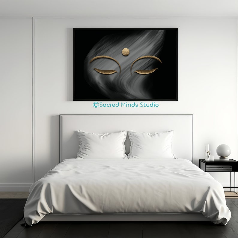 Puede incluir: Una impresi&oacute;n de arte abstracto en blanco y negro con una cara de Buda dorada con los ojos cerrados. La impresi&oacute;n est&aacute; colgada en una pared blanca sobre una cama blanca con ropa de cama blanca.